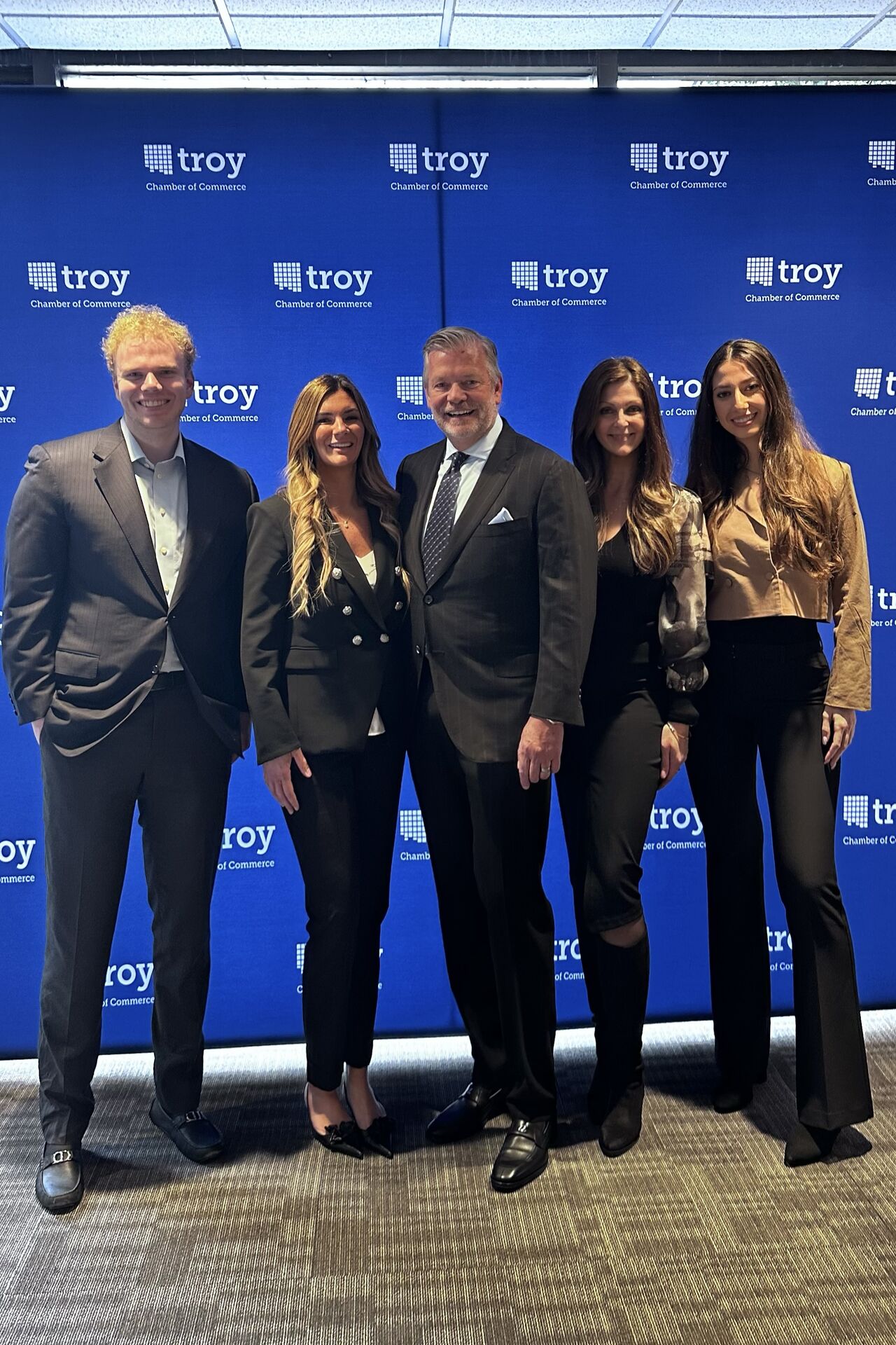 People stand in front of a Troy Chamber of Commerce backdrop.
